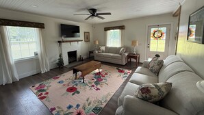A living room with a fireplace, a ceiling fan, a sofa, a coffee table, and a floral rug.