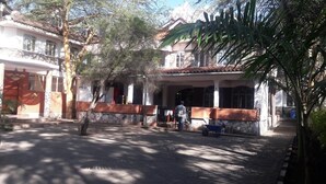 Um pátio com um edifício de telhado em azulejos, paredes de pedra e uma área coberta com colunas.