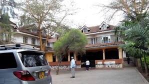 Uma área residencial com um carro estacionado, um edifício com telhado de cerâmica e uma galeria coberta.