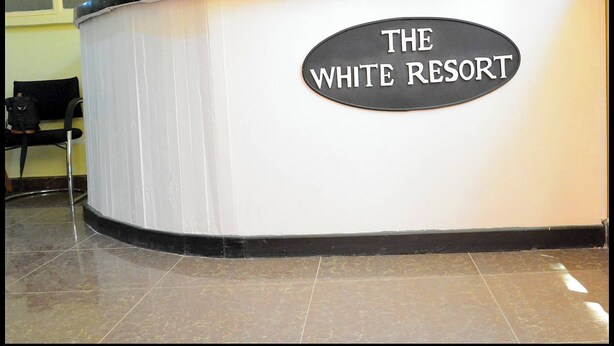 Um balcão de recepção com uma placa que diz "THE WHITE RESORT".