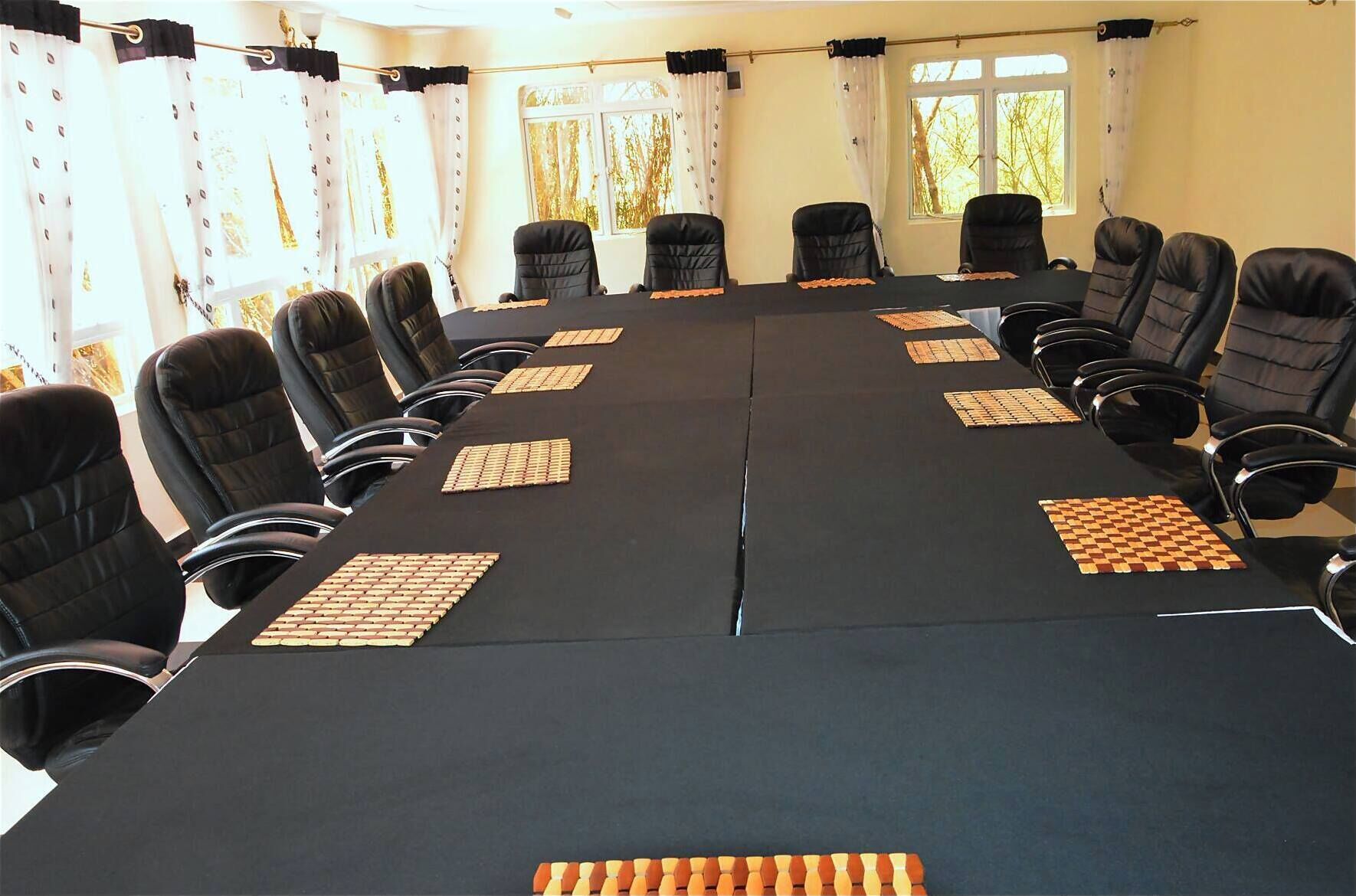 A conference room with a long table, black chairs, and chess boards.