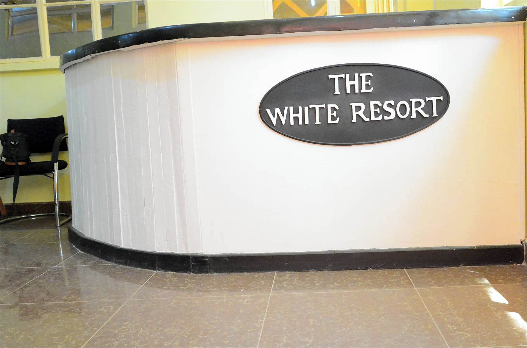 A reception desk with a sign that reads "THE WHITE RESORT".