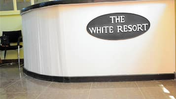 Un mostrador de recepción con un cartel que dice 'THE WHITE RESORT'.