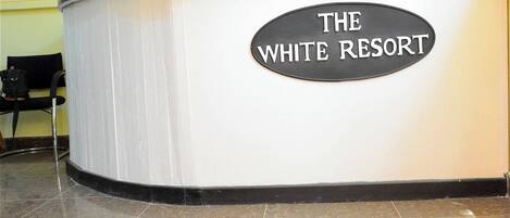A reception desk with a sign that reads "THE WHITE RESORT".