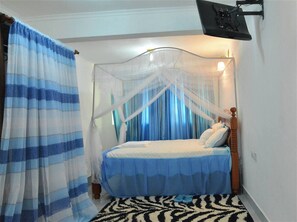 Um quarto com uma cama, uma mosquiteira e uma mesa de cabeceira.