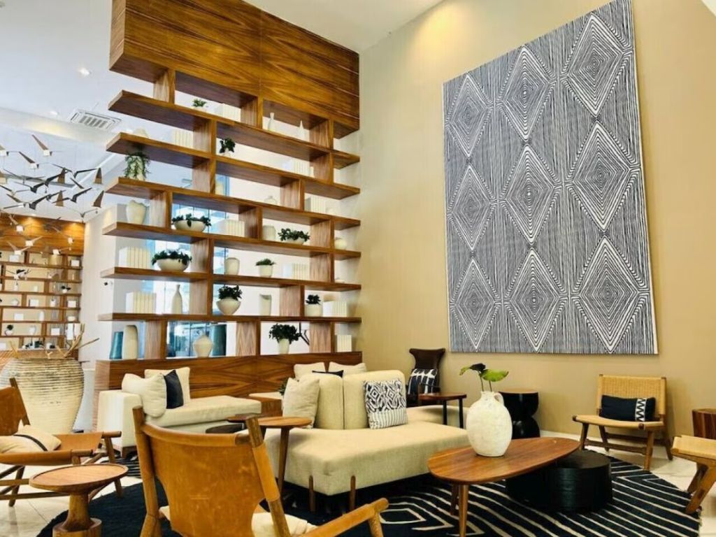A modern living room with a sofa, chairs, a coffee table, a bookshelf, and a large abstract painting.