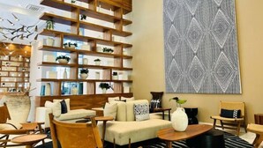 Een moderne woonkamer met een bank, fauteuils, een salontafel, een boekenkast en een groot abstract schilderij.