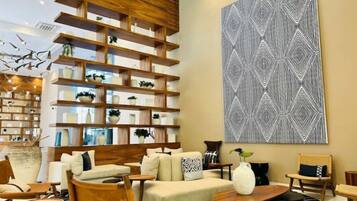A modern living room with a sofa, chairs, a coffee table, a bookshelf, and a large abstract painting.