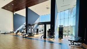 Een sportschool met trainingsapparatuur, grote ramen en een houten vloer.