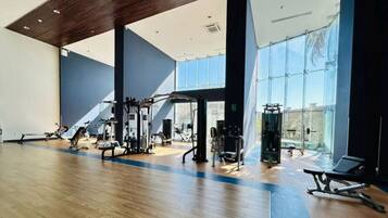 A gym with exercise equipment, large windows, and a wooden floor.
