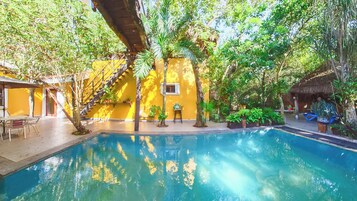 Una piscina al aire libre, sombrillas, sillones reclinables de piscina