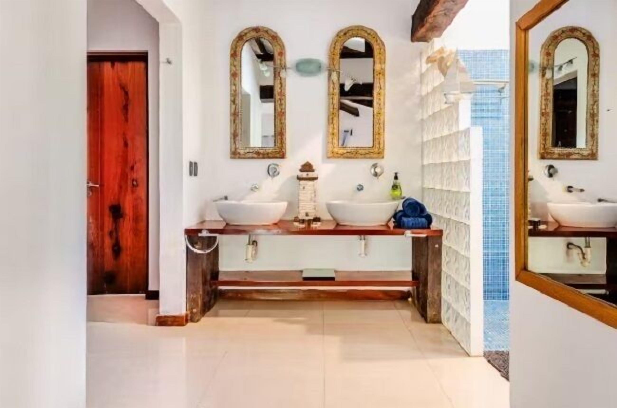 A bathroom with two sinks, a wooden vanity, and a mirror with an ornate frame.