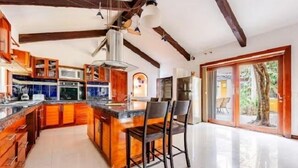 A spacious kitchen with wooden cabinets, a central island, and a large window. - Villa con Piscina y Acceso a Laguna Yalkú, Akumal (Akumal)