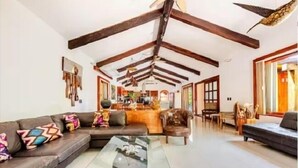 A spacious living area with a high ceiling, a sofa set, a coffee table, and a dining area with chairs. - Villa con Piscina y Acceso a Laguna Yalkú, Akumal (Akumal)