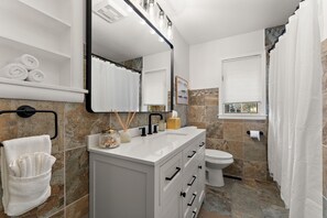 Une salle de bain moderne avec un meuble-lavabo blanc, un grand miroir et des toilettes.