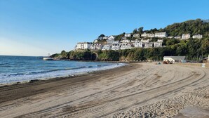 A wide sandy beach with a clear view of the ocean and a hillside of white buildings. - Looe Cottage - Seaside views, log fire, sleeps 4 (Looe)