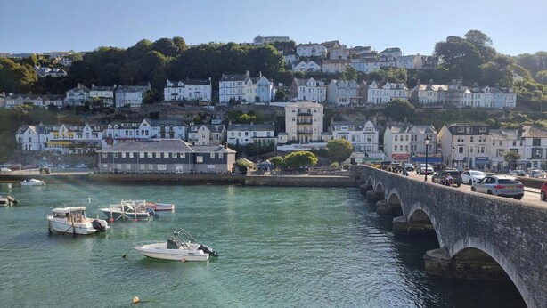 A coastal town with a stone bridge over a calm harbor, boats docked, and buildings on a hillside. - Looe Cottage - Seaside views, log fire, sleeps 4 (Looe)