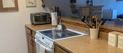 Una cocina con armarios de madera, estufa, microondas y tostadora.