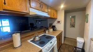 A compact kitchen with wooden cabinets, a gas stove, an oven, and a coffee maker. - Charming 1-bedroom condo in Frisco (Frisco)