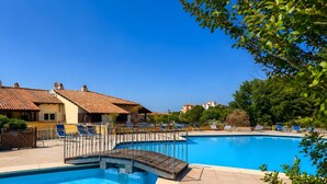 A swimming pool with a wooden deck, lounge chairs, and a building with a tiled roof. - Rotondo Dream Suite 1, Porto Rotondo, Italy (Porto Rotondo)