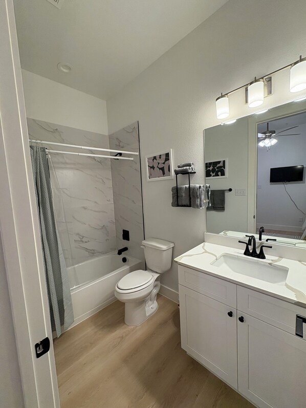 A modern bathroom with a shower, toilet, and vanity.