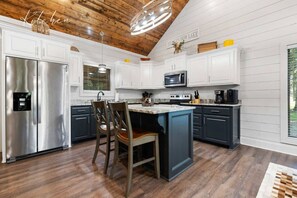A kitchen with white cabinetry, a stainless steel refrigerator, a microwave, and a coffee maker.