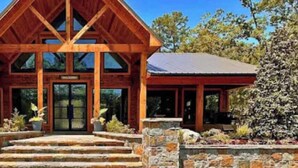 A wooden lodge with a triangular roof, stone steps leading to the entrance, and a sign above the door.