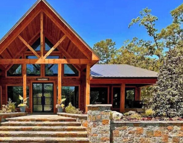 A wooden lodge with a triangular roof, stone steps leading to the entrance, and a sign above the door.