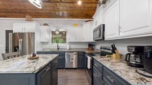 A modern kitchen with granite countertops, stainless steel appliances, and dark cabinetry.