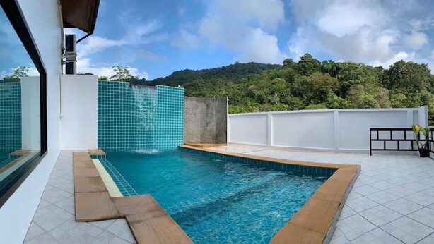 A rooftop swimming pool with a view of a forested hill. - Hillside Studio Vacation Apartment with Pool (Kamala, Kathu District, Phuket)