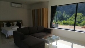 A modern living room with a sectional sofa, a glass coffee table, and a bed with a headboard. - Hillside Studio Vacation Apartment with Pool (Kamala, Kathu District, Phuket)