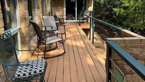 A wooden deck with outdoor furniture, a small dog, and a building with a green roof. - Peaceful Retreat w/Lakeview in Hot Springs Village (Hot Springs Village)
