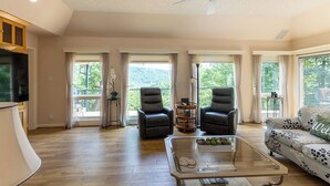 A spacious living room with a ceiling fan, two leather chairs, a glass coffee table, and a sofa with a floral pattern. - Peaceful Retreat w/Lakeview in Hot Springs Village (Hot Springs Village)