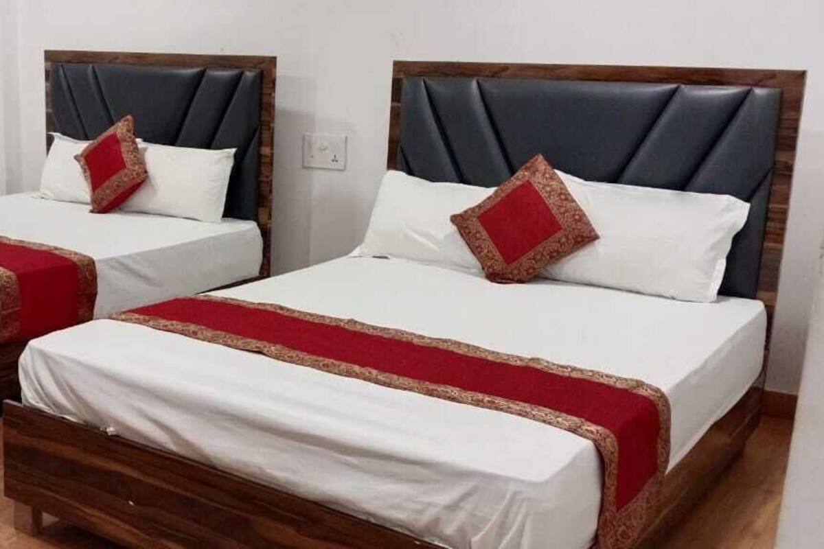 Two twin beds with wooden frames and white bedding, each with a red and gold decorative trim.