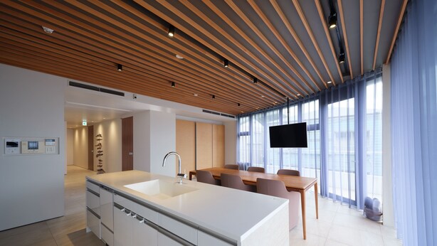 A modern kitchen with a large island, wooden ceiling, and a dining area with a TV. - lili villa hayama (Hayama)