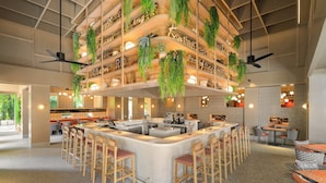 Een ruime binnenruimte met een centrale bar, diverse zithoeken en hangende beplanting.