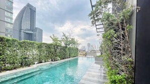 A rooftop swimming pool with a city skyline in the background.
