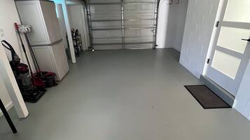 Un garaje limpio y vacío con una puerta cerrada, un ventilador de techo y un extintor rojo montado en la pared.