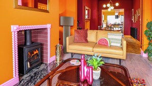Una sala de estar acogedora con chimenea, un sofá y una zona de comedor al fondo.