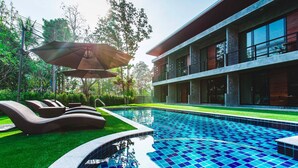 A modern hotel with a swimming pool, outdoor seating, and a large umbrella. - stucco loft residency (Chiang Mai)
