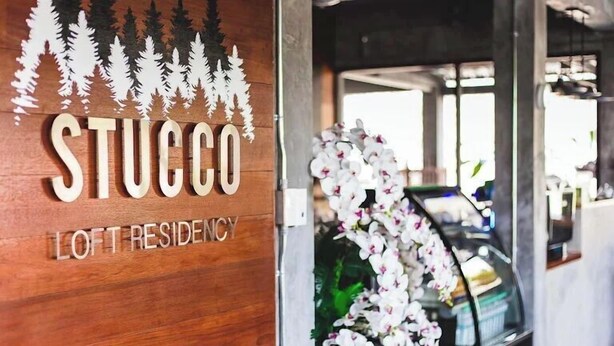 A wooden sign with "STUCCO LOFT RESIDENCY" and a decorative arch of white flowers. - stucco loft residency (Chiang Mai)