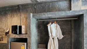 A compact kitchenette with a microwave, a small refrigerator, and a radio. A robe hangs on a rack above a bench with a pair of slippers. - stucco loft residency (Chiang Mai)