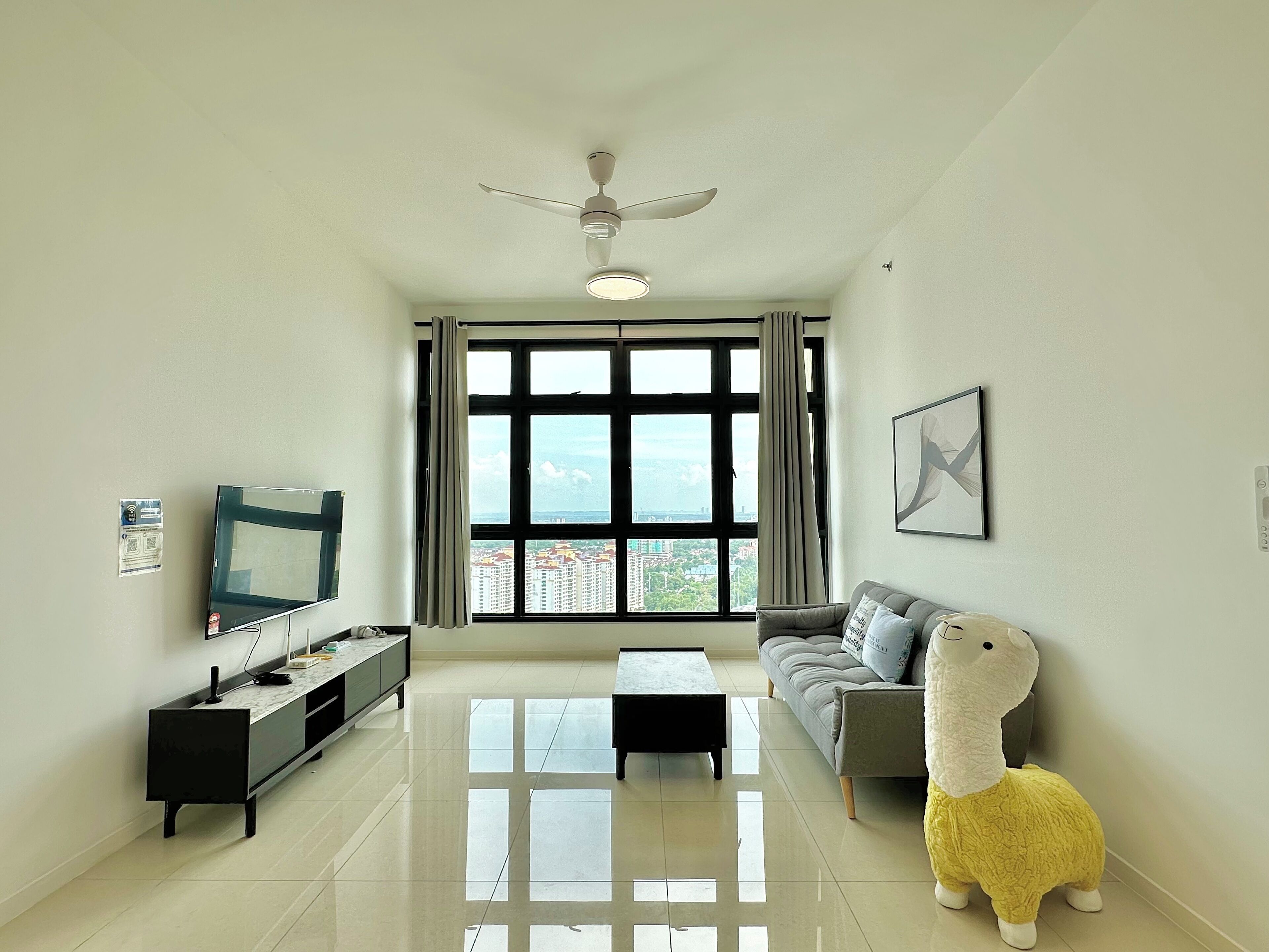 A modern living room with a flat-screen TV, a sofa, a coffee table, and a ceiling fan.