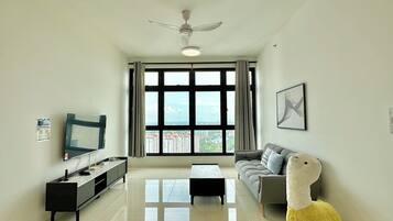 A modern living room with a flat-screen TV, a sofa, a coffee table, and a ceiling fan.