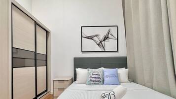 Una habitación de hotel moderna con una cama grande, una mesita de noche, un armario y una obra de arte enmarcada en la pared.