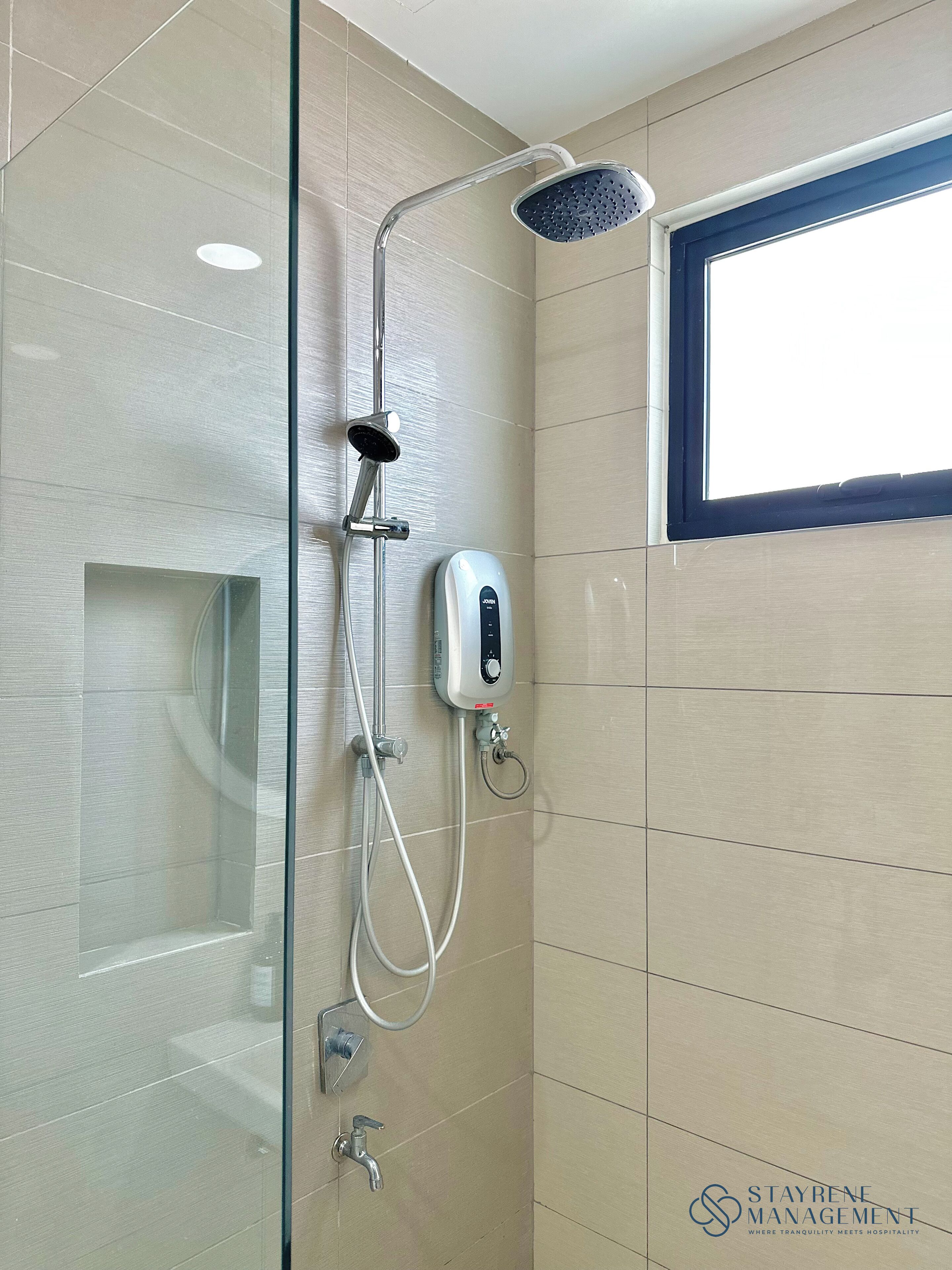 Ducha con cabezal de ducha de mano, panel de control en la pared y zona de ducha con mampara de vidrio.