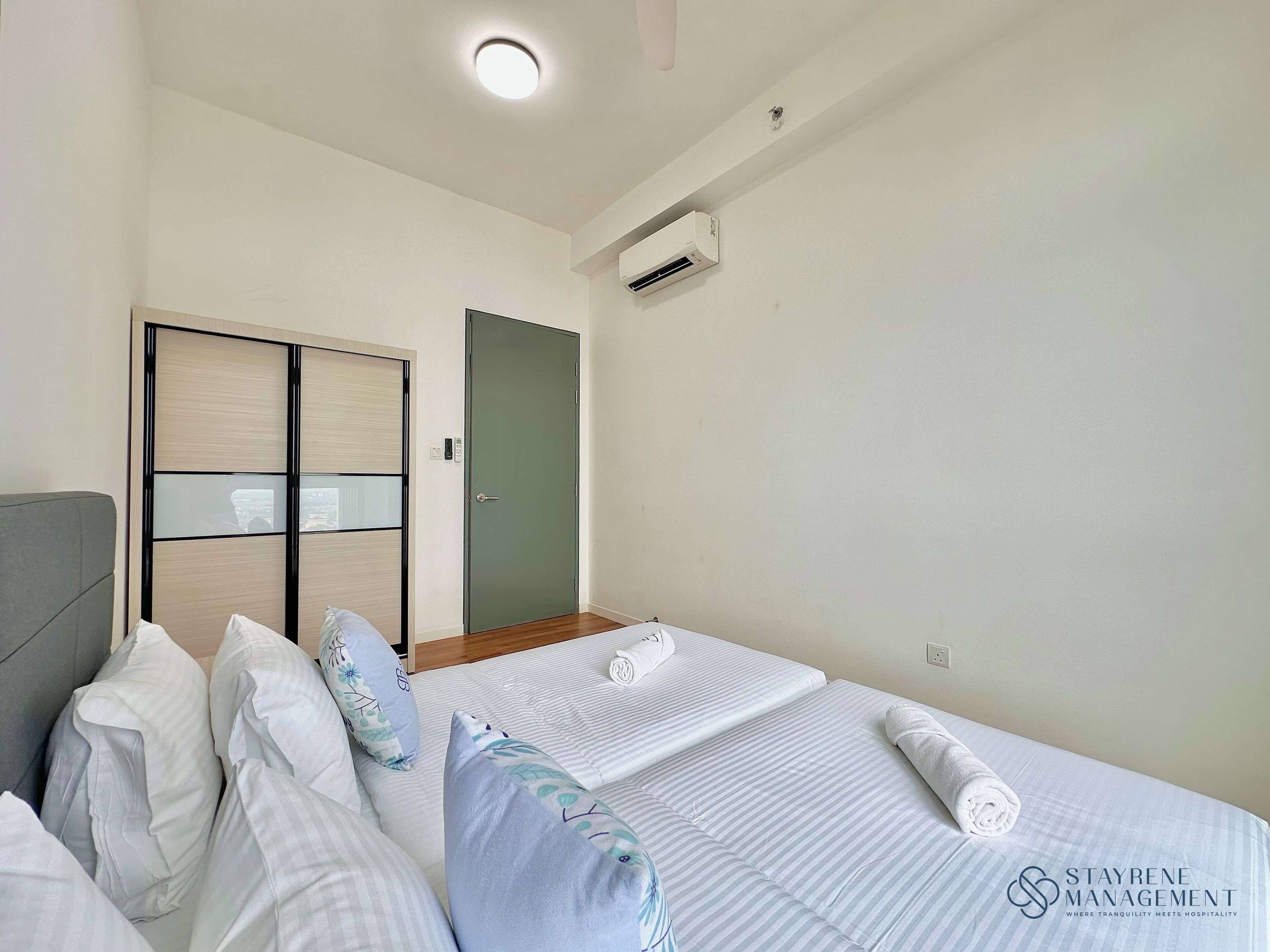 Camera d'albergo con letto, cuscini, armadio, condizionatore d'aria e una lampada a soffitto.