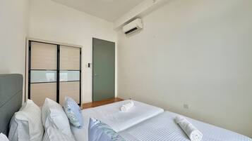 Camera d'albergo con letto, cuscini, armadio, condizionatore d'aria e una lampada a soffitto.