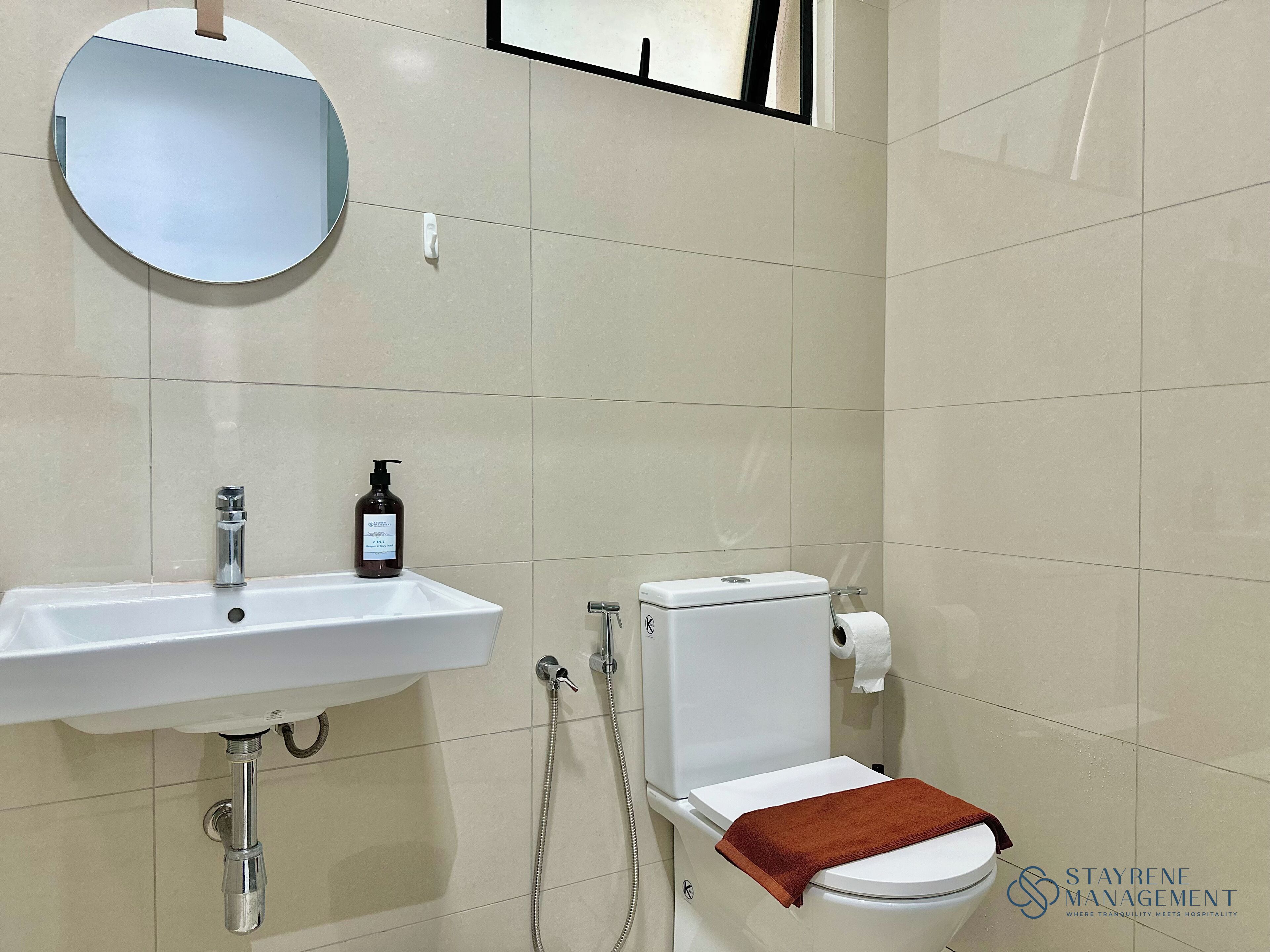 A bathroom with a white sink, a mirror, a toilet, and a shower.