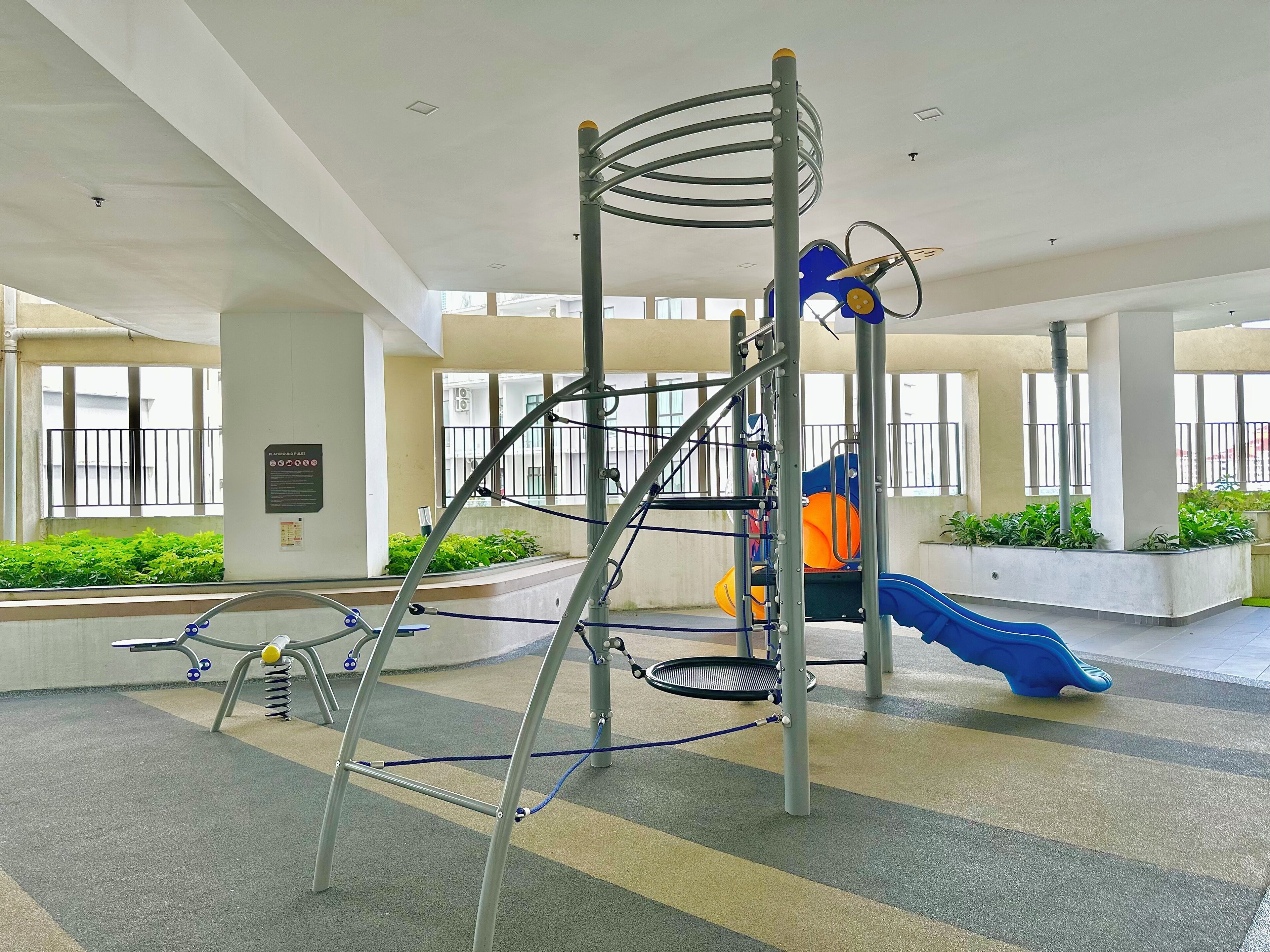 Ein Spielplatz mit Rutsche und Klettergerüsten in einem Innenbereich.